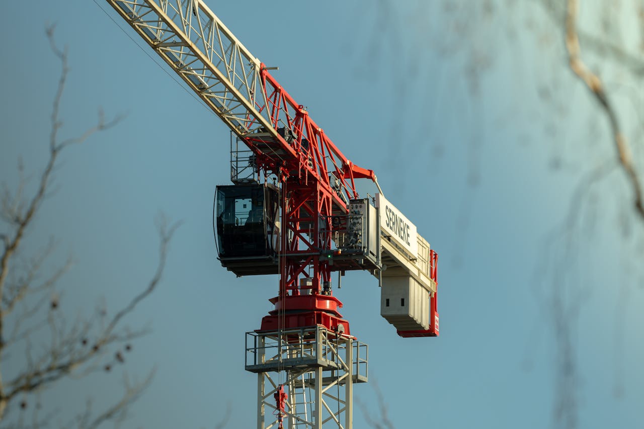 Close-up of a red tower crane with clear blue sky background, highlighting construction industry.